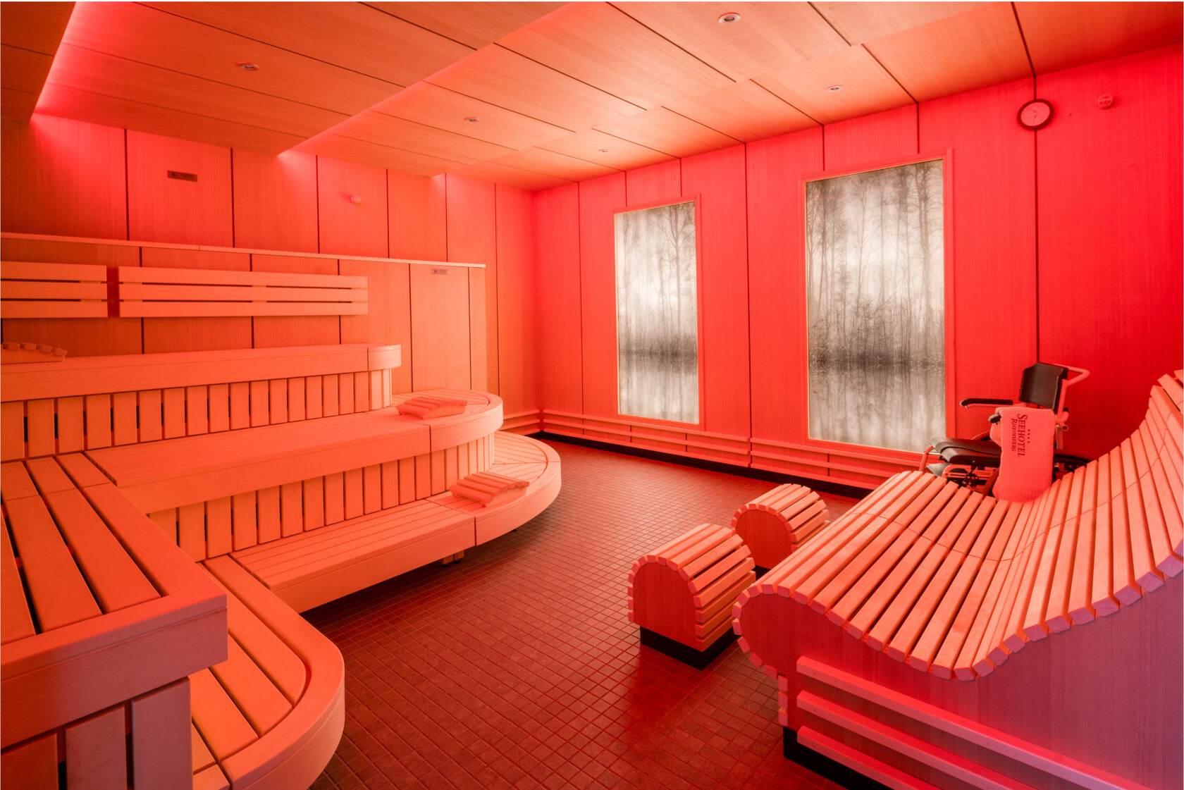 Gesamtansicht der rot beleuchteten Sauna mit Waldhintergrundsbild